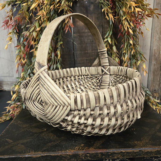 Woven basket with geometric pattern on a rustic wooden surface with greenery