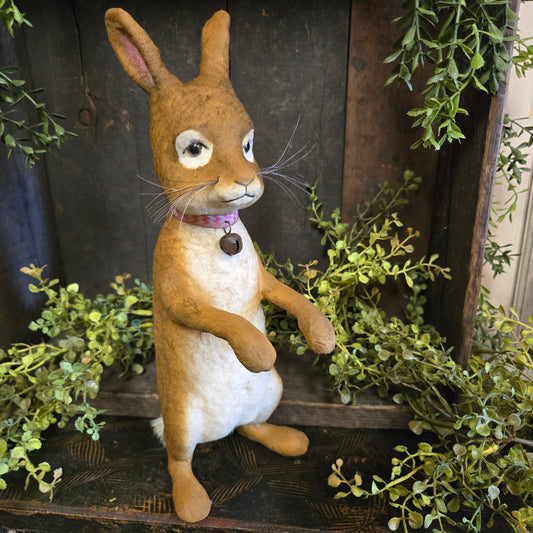Plush toy rabbit lying on a wooden surface with greenery