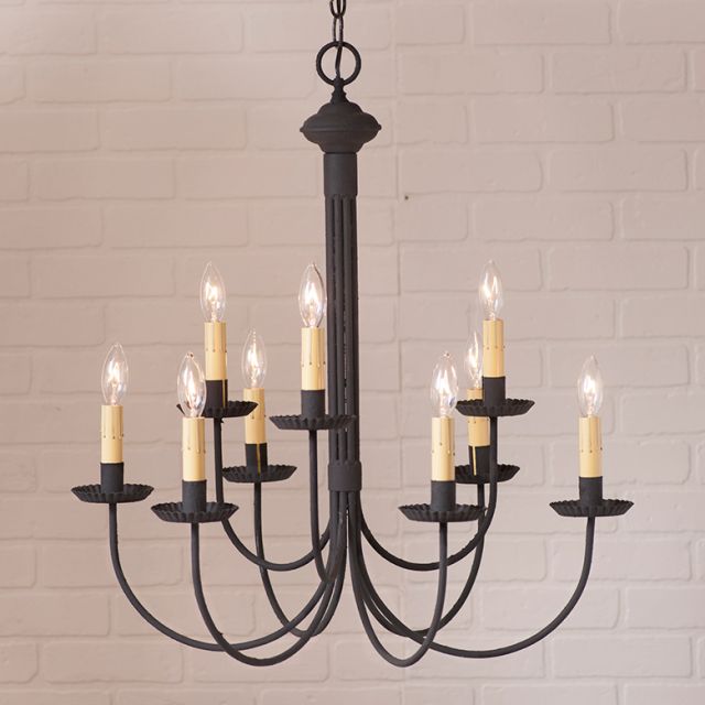 Black chandelier hanging in front of cream brick wall