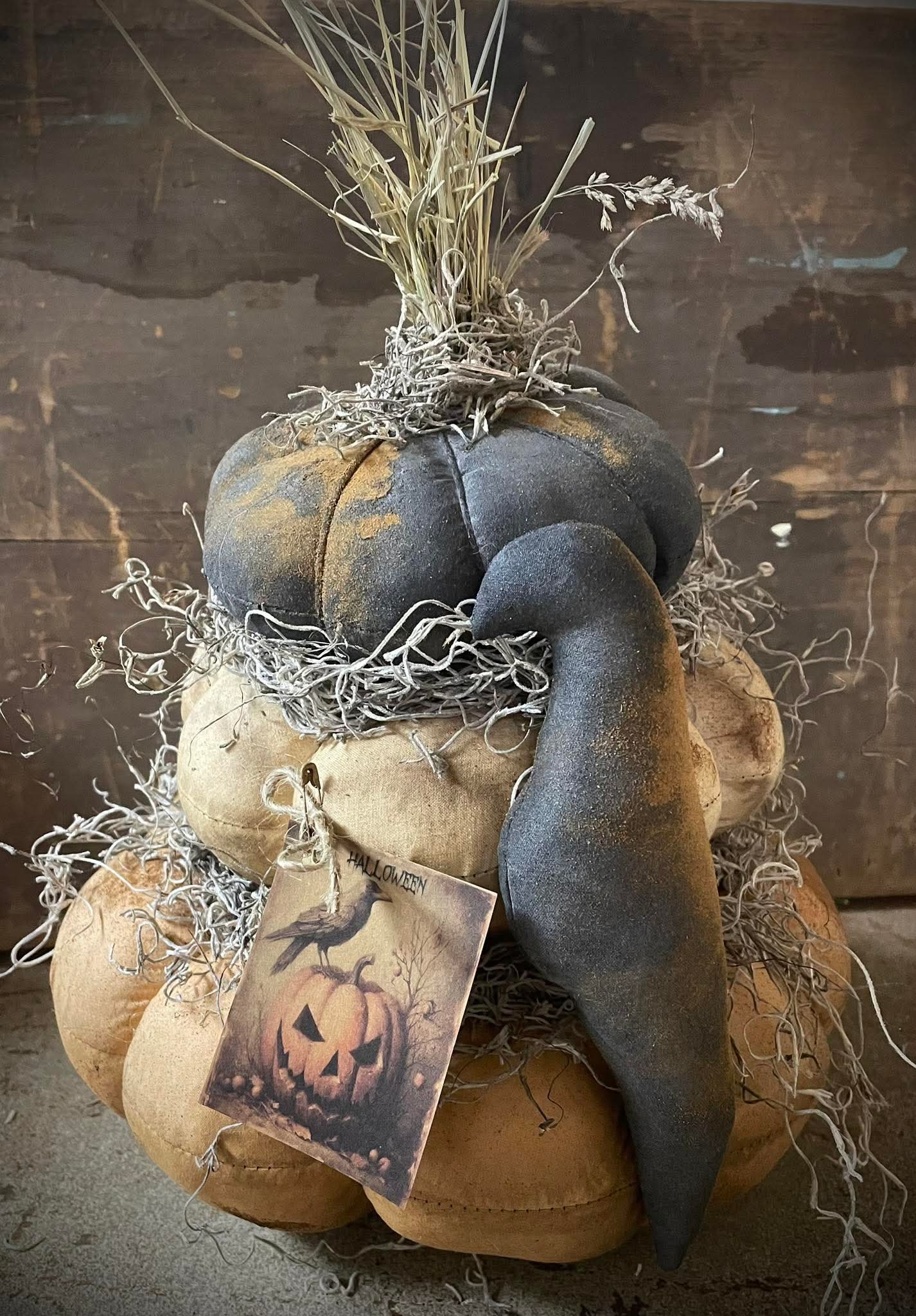 Decorative arrangement of pumpkins with a tag featuring a jack-o'-lantern design on a rustic wooden background.