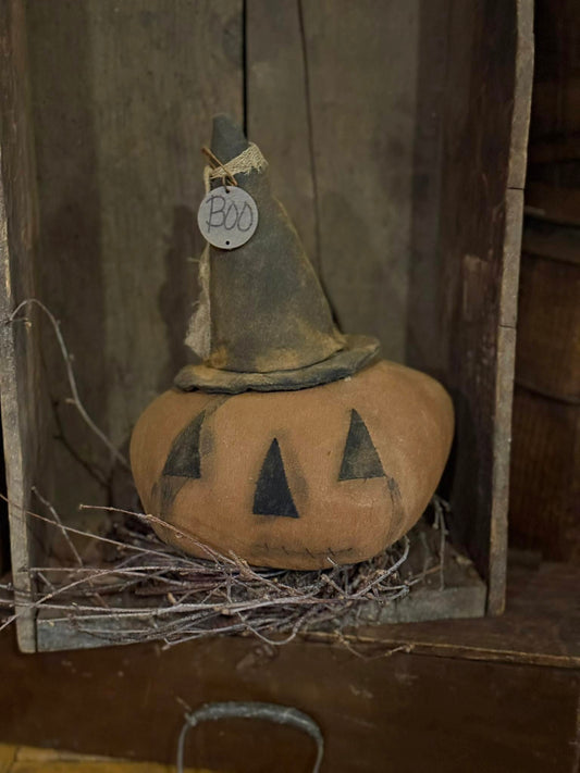 Decorative pumpkin with a witch hat and 'BOO' tag on a rustic background