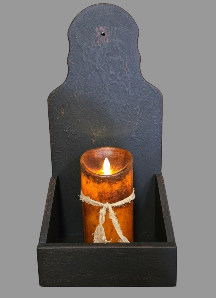 A black wooden sconce candle holder mounted on a wall, holding a candle with a warm glow.