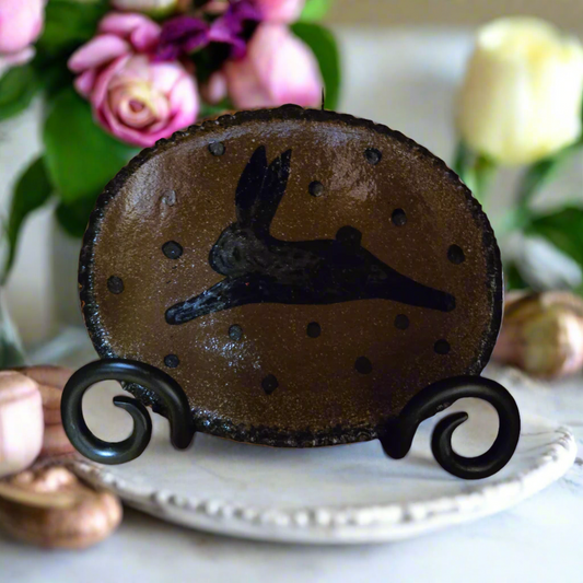 Decorative piece with a rabbit silhouette on a stand, flowers in the background