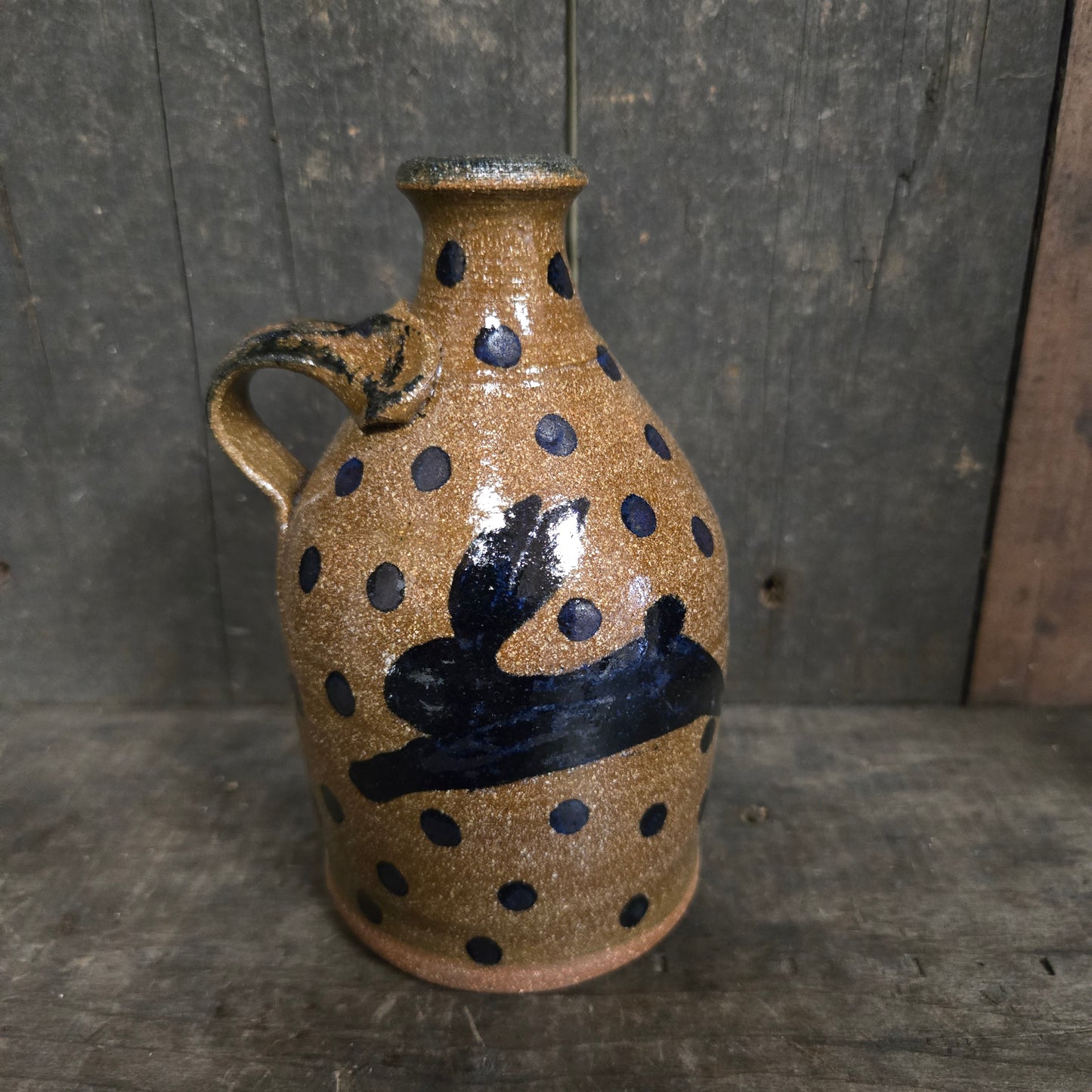 Ceramic vase with black dot patterns on a wooden surface
