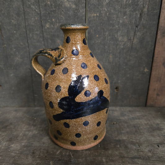Ceramic vase with black dot patterns on a wooden surface