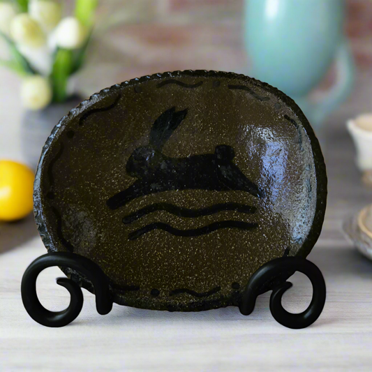 Small oval stoneware plate with a leaping bunny over squiggles with a decorative border