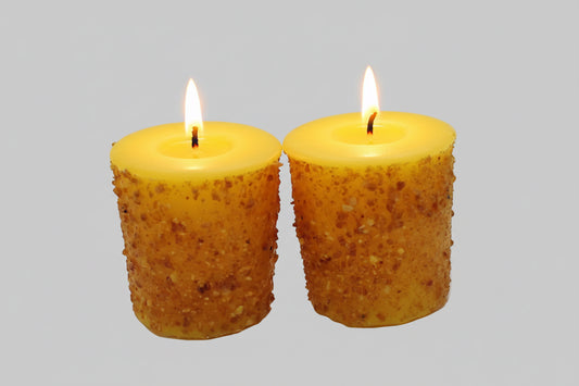Two yellow textured candles on a white background
