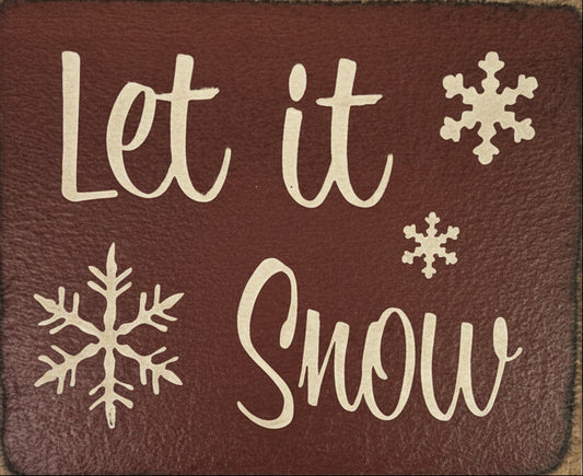 Decorative sign with 'Let it Snow' text and snowflake designs on a brown background