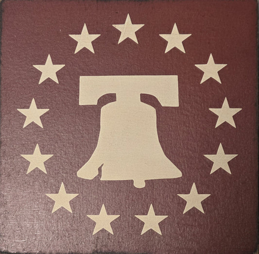 Wooden block with a cutout of the Liberty Bell surrounded by stars on a red background