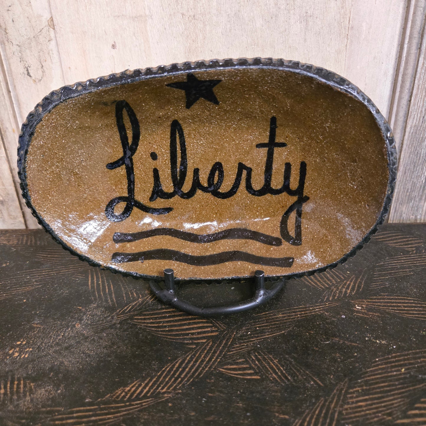 Decorative stoneware plate with 'Liberty' design on a wooden surface