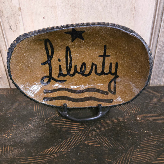 Decorative stoneware plate with 'Liberty' design on a wooden surface