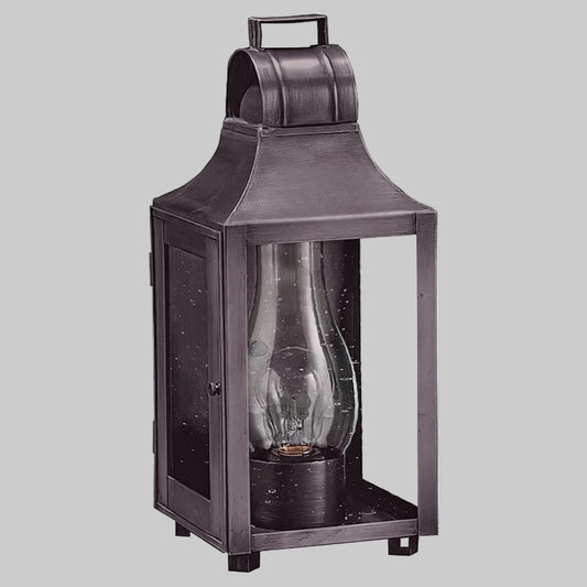 Dark metal lantern with a clear glass cover on a gray background