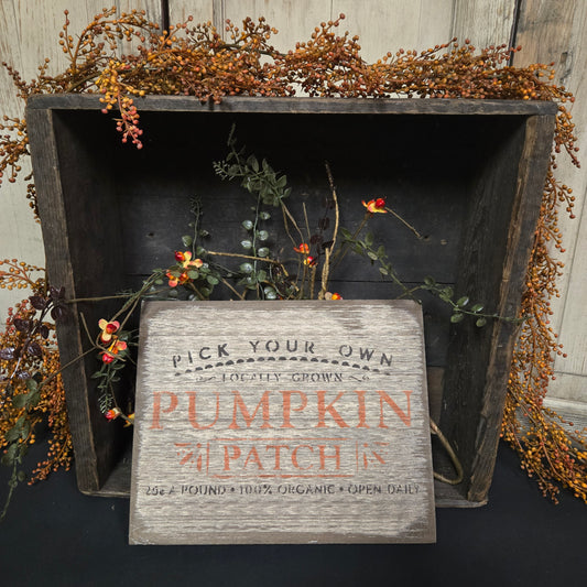 Wooden box with 'Pick Your Own Pumpkin Patch' sign surrounded by autumnal decorations.