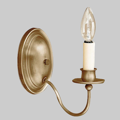Brass wall sconce with a single light bulb on a gray background