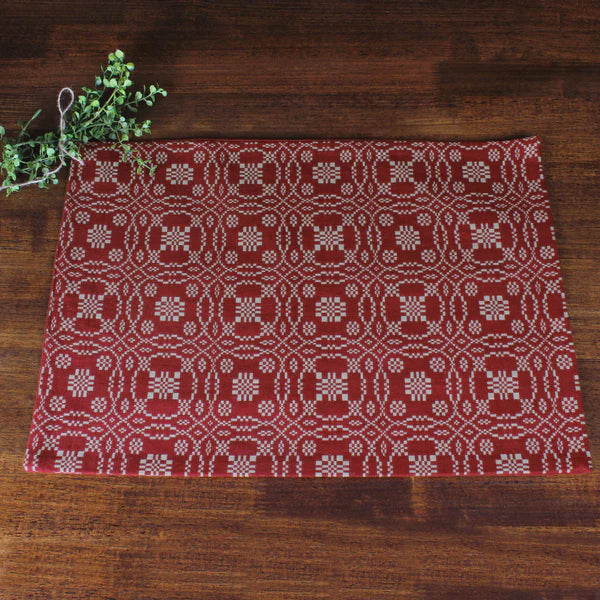 Lover's knot barn red placemat on wooden table with greenery