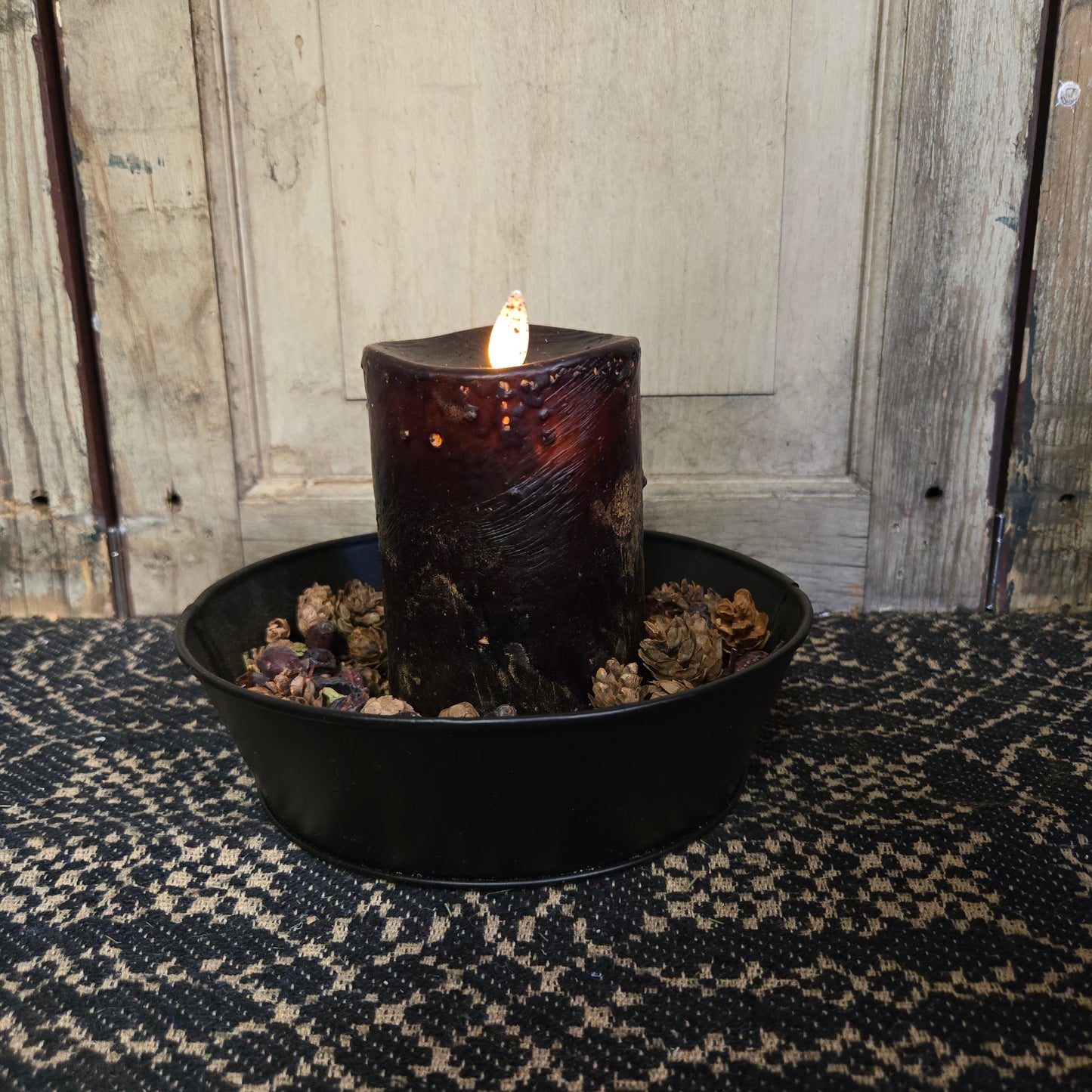 A black moving flame pillar candle on a rustic background