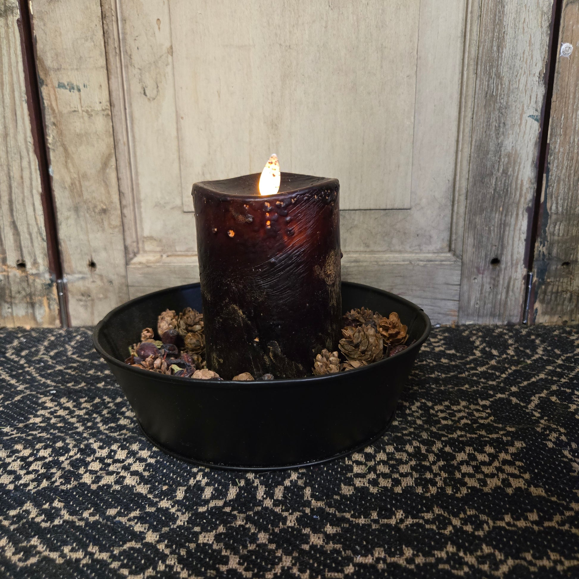A black moving flame pillar candle on a rustic background