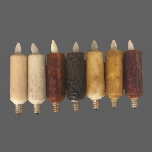 Seven Luminara candle-style moving flame bulbs in cream, brown, black, gold, and burgundy finishes with screw-in bases against a gray background.