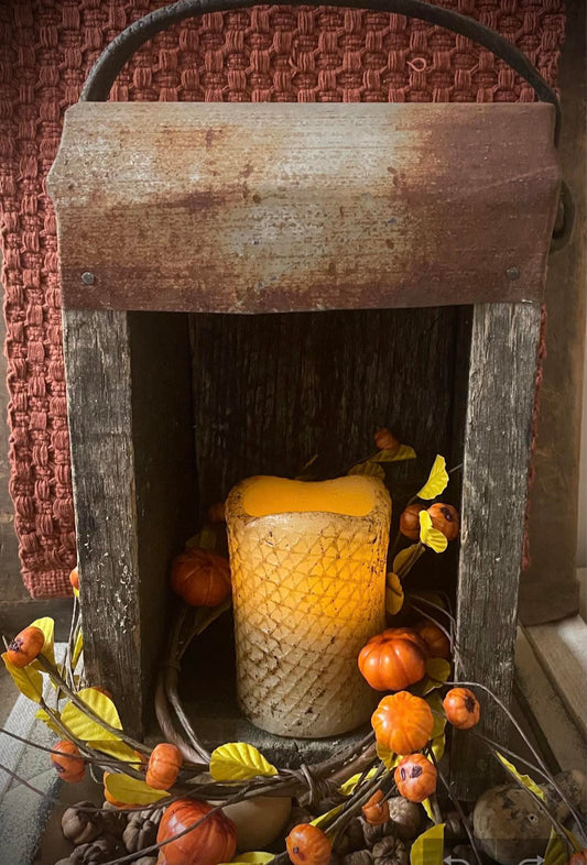 Decorative fireplace with a lit candle, pumpkins, and autumn leaves.