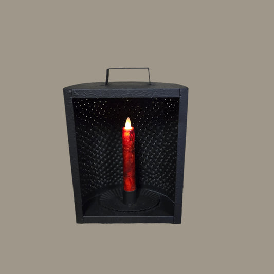 A black metal mantle light candle holder with a battery operated taper candle inside, displaying a red glow through the perforated holes.