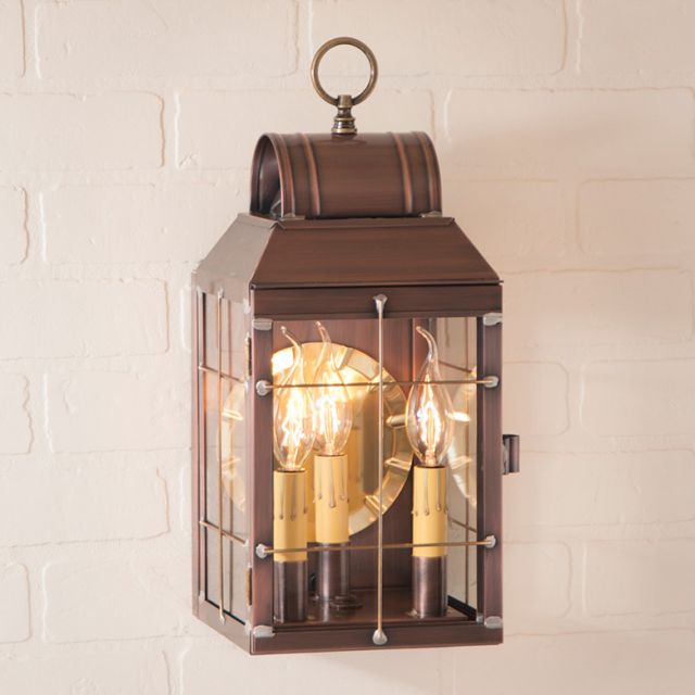 Decorative wall lantern with glass panels on a white brick wall background