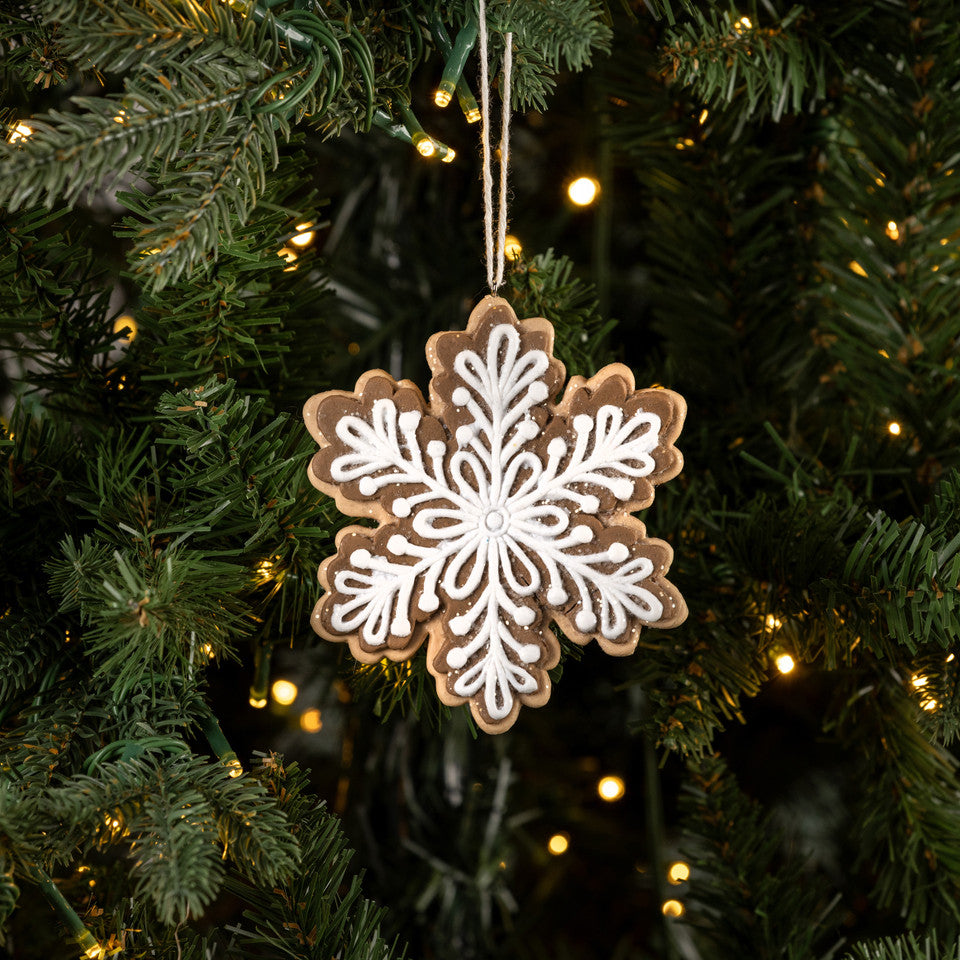 Decorative snowflake ornament on a Christmas tree with lights.