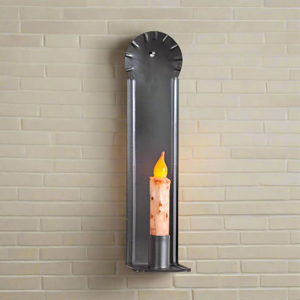 A black metal candle sconce with a candle holder mounted on a white wooden wall.