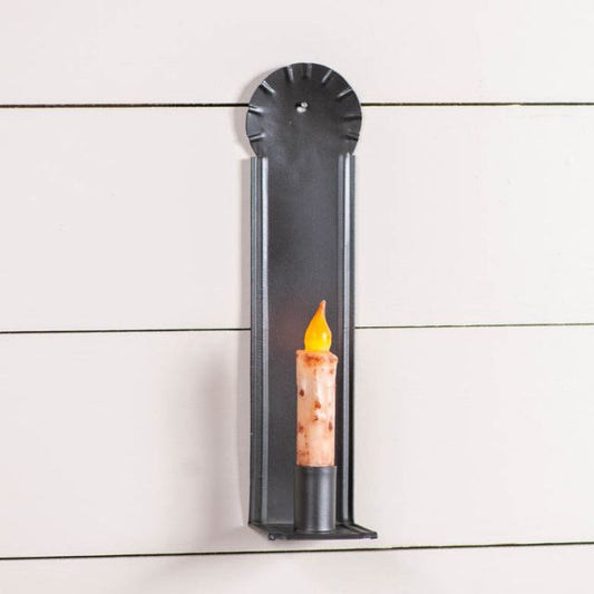 A black metal candle sconce with a candle holder mounted on a white wooden wall.