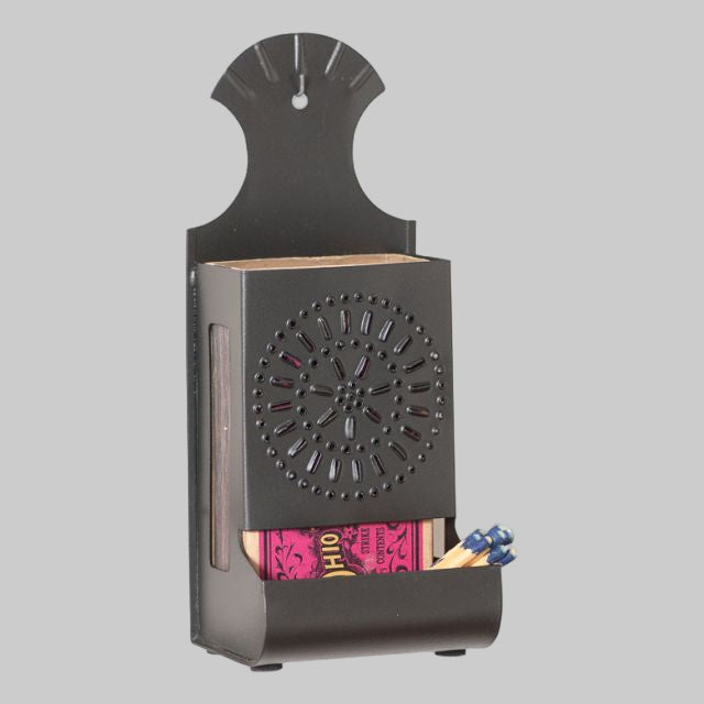 A smokey black metal match box with a solid pattern, featuring a circular design on the top and a compartment for matches at the bottom.