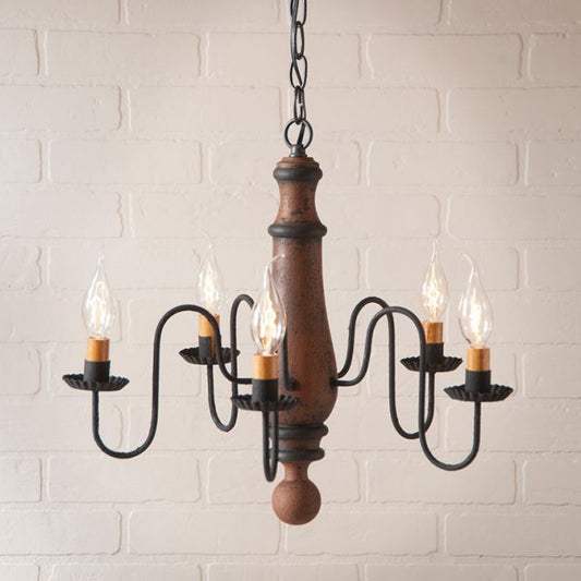 Wooden and metal chandelier with five light bulbs against a white brick wall.