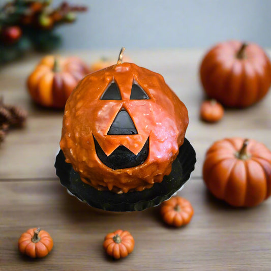 Pumpkin-shaped cake with jack-o'-lantern face on a wooden table with small pumpkins around