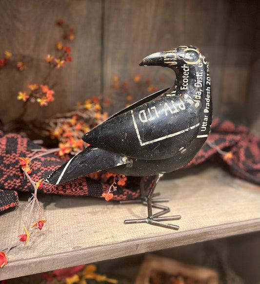 Decorative black bird figure on a wooden surface with a rustic background