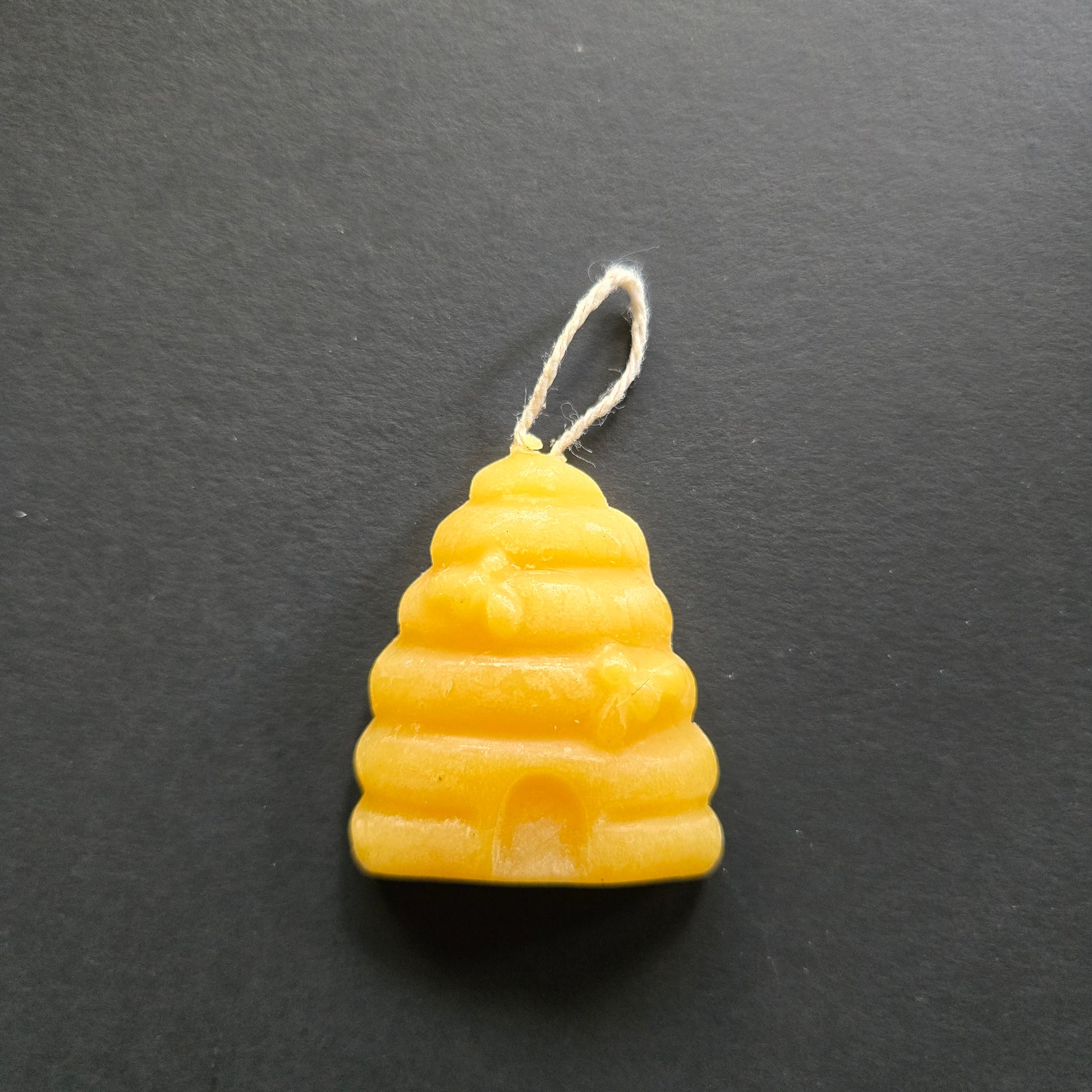 Yellow bee skep-shaped candle on a dark gray background