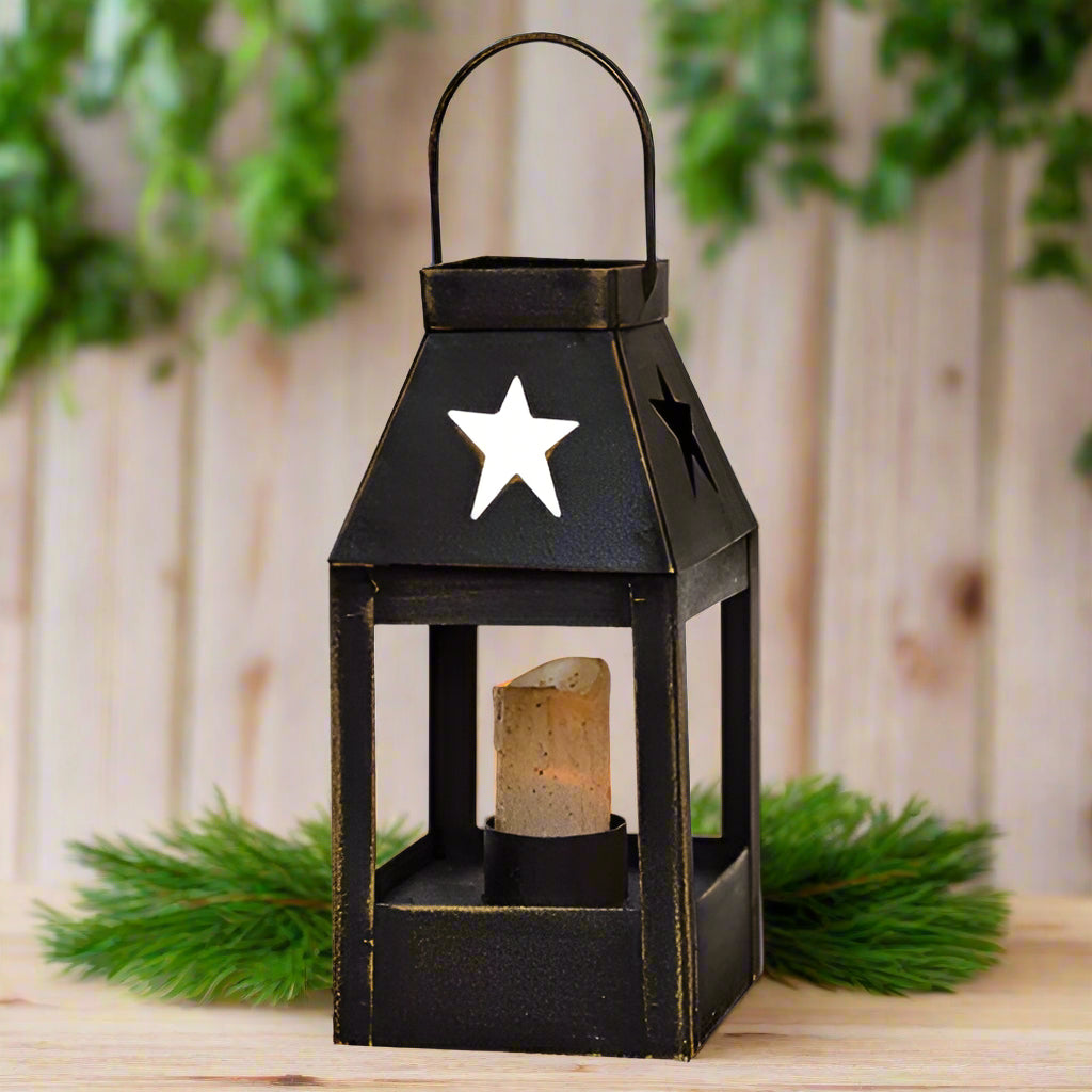 A black mini star-shaped lantern with a handle on top, featuring four star cut-outs, a wax LED drip candle, and two button batteries.