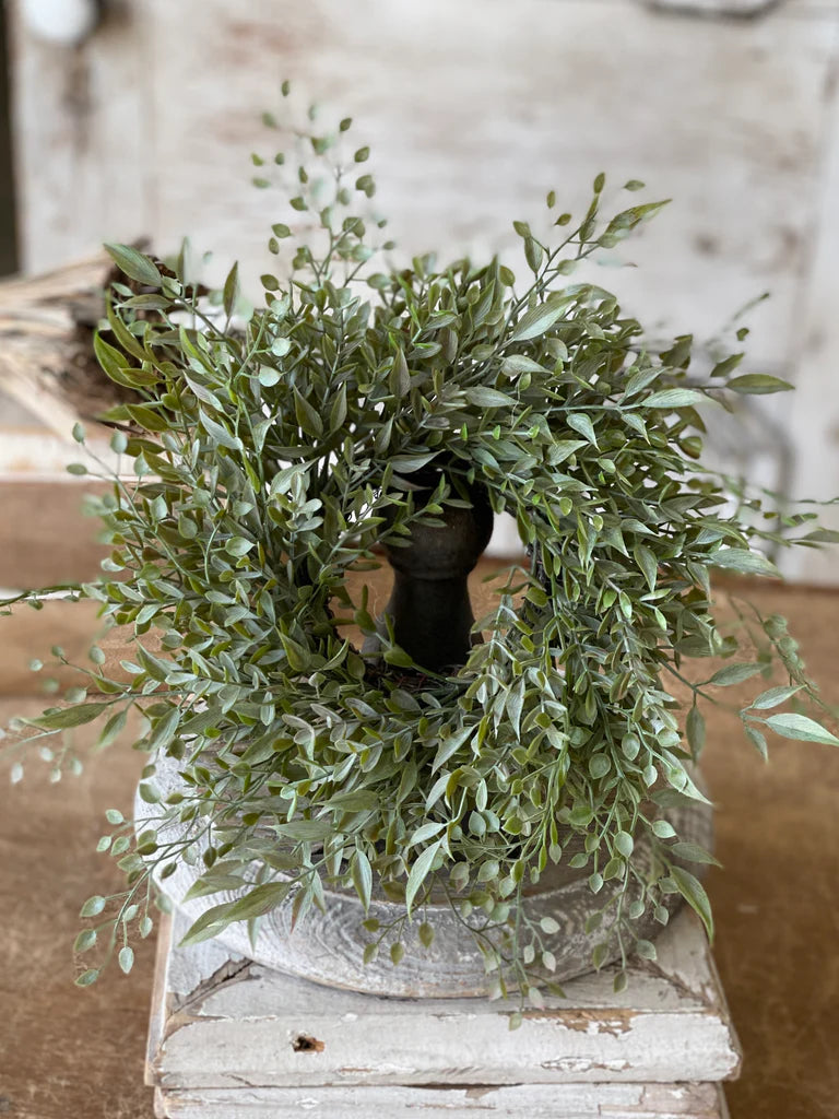 Green leafy wreath on a wooden surface with a blurred background