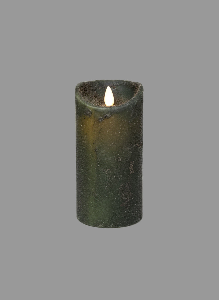 A pillar candle with a moving flame, encased in a dark green wreath, placed on a textured mat.