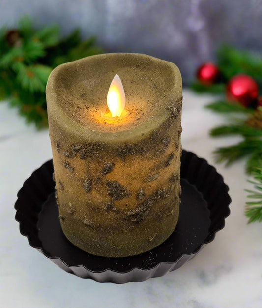 A green pillar candle with a moving flame effect, placed on a black dish. The candle is illuminated from the top, simulating a real flame.