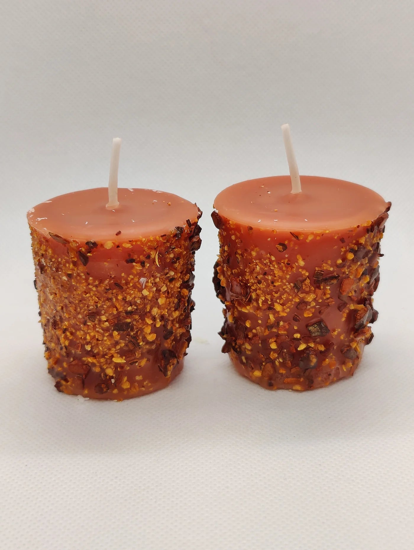 Two textured red candles on a white background