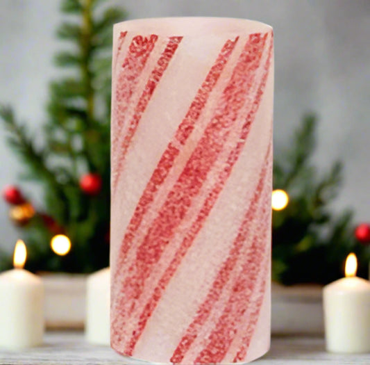 A battery-operated pillar candle with a warm glow, featuring a striped, red and white candy cane design, coated in glitter and icy frost.