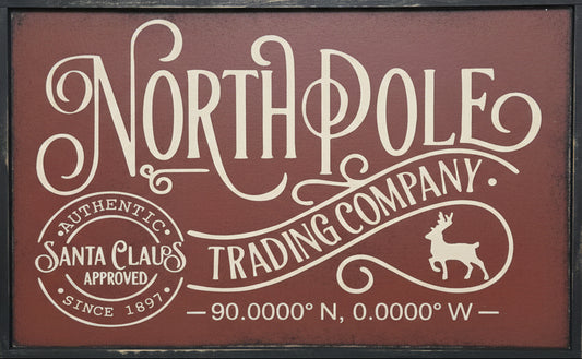 Decorative sign with 'North Pole Trading Company' text on a wooden background