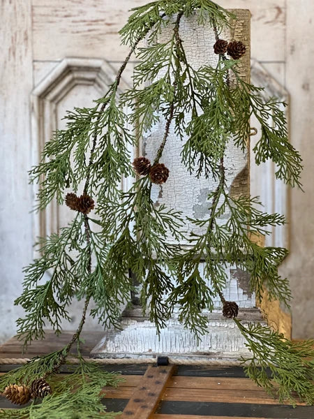 Greenery with pinecones on a rustic wooden surface