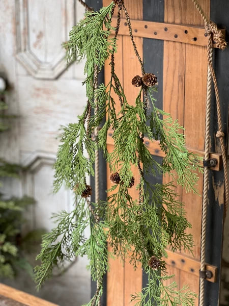 Hanging evergreen garland with pinecones on a wooden door