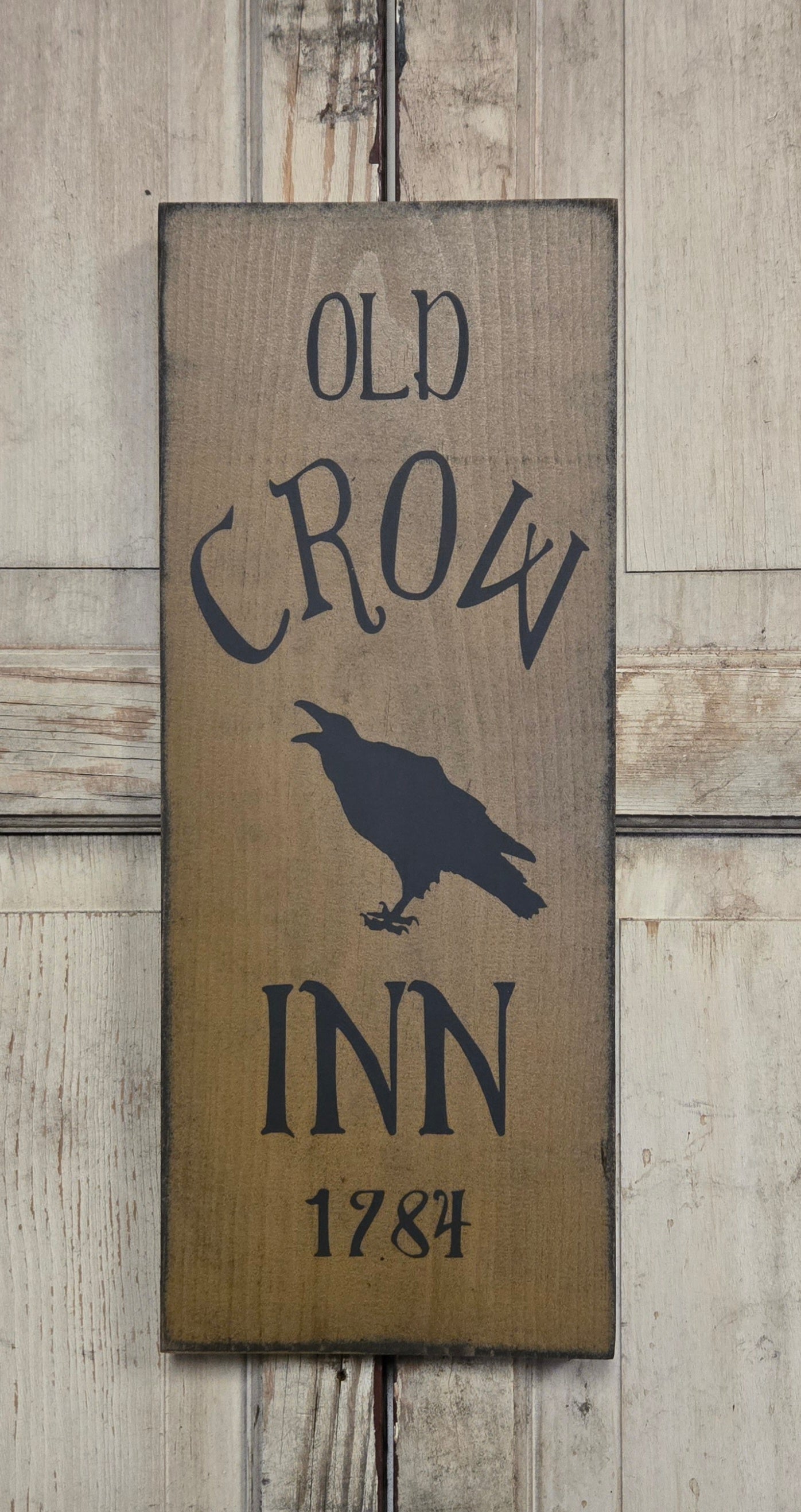 Wooden sign with 'Old Crow Inn 1784' text and crow silhouette on a wooden background