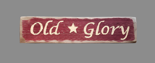 Weathered wood sign painted red with the words "Old Glory" and a star in the middle in cream