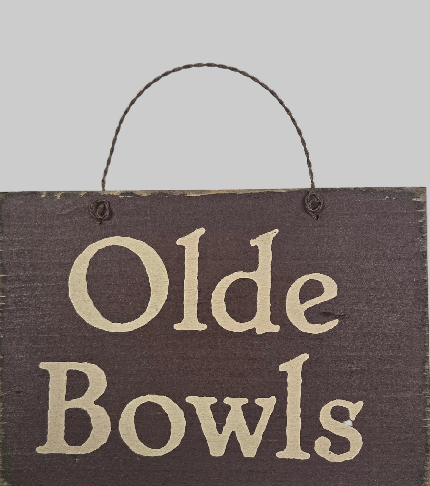 Wooden sign with 'Olde Bowls' text on a white background