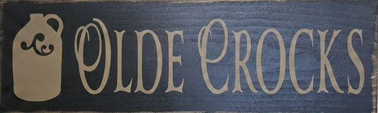 Wooden sign with 'Olde Crocks' text and logo on a wooden background