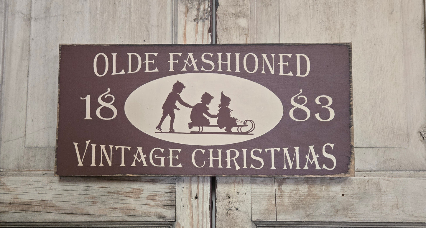 Vintage-style Christmas sign with silhouettes of children and text on a wooden background