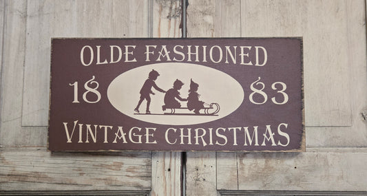 Vintage-style Christmas sign with silhouettes of children and text on a wooden background