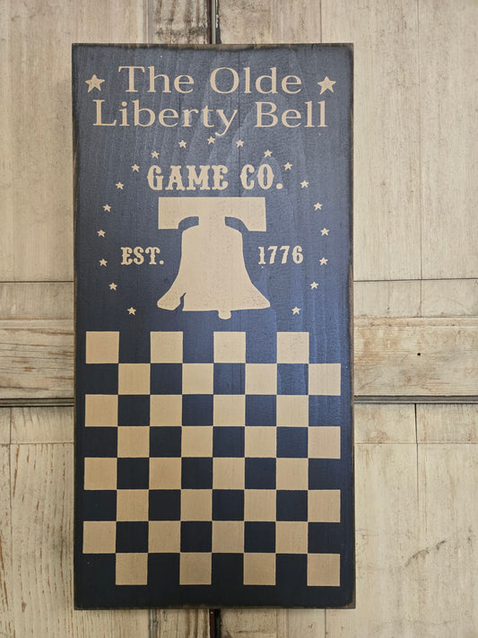Checkered design with 'The Olde Liberty Bell Game Co.' branding on a wooden door.