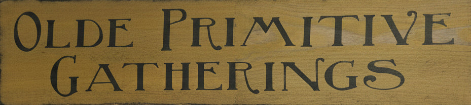 A rustic rectangular wooden sign with the words 'OLDE PRIMITIVE GATHERINGS' in dark lettering.
